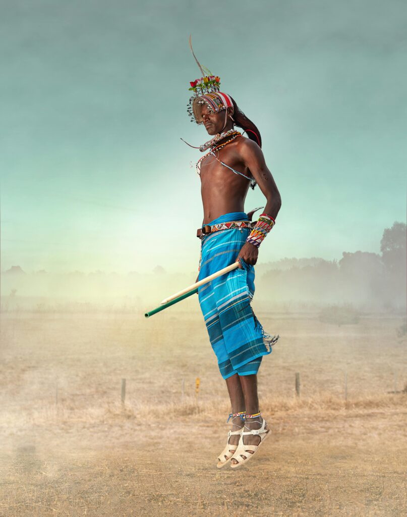 A Maasai warrior in traditional attire jumps high, showcasing cultural dance in Kenya.
